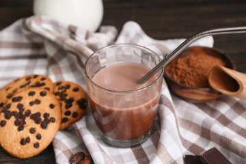 Glass of sweet chocolate milk and tasty cookies on wooden background