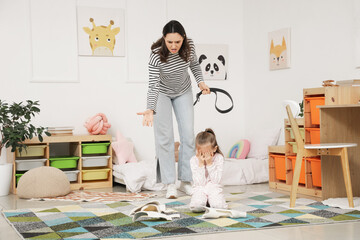 Angry mother with belt scolding her little daughter for broken vase in bedroom. Domestic violence...