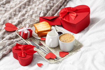 Tray with breakfast and gift boxes for Valentine's Day on bed