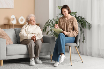 Obraz premium Young nurse writing in clipboard with senior woman at home