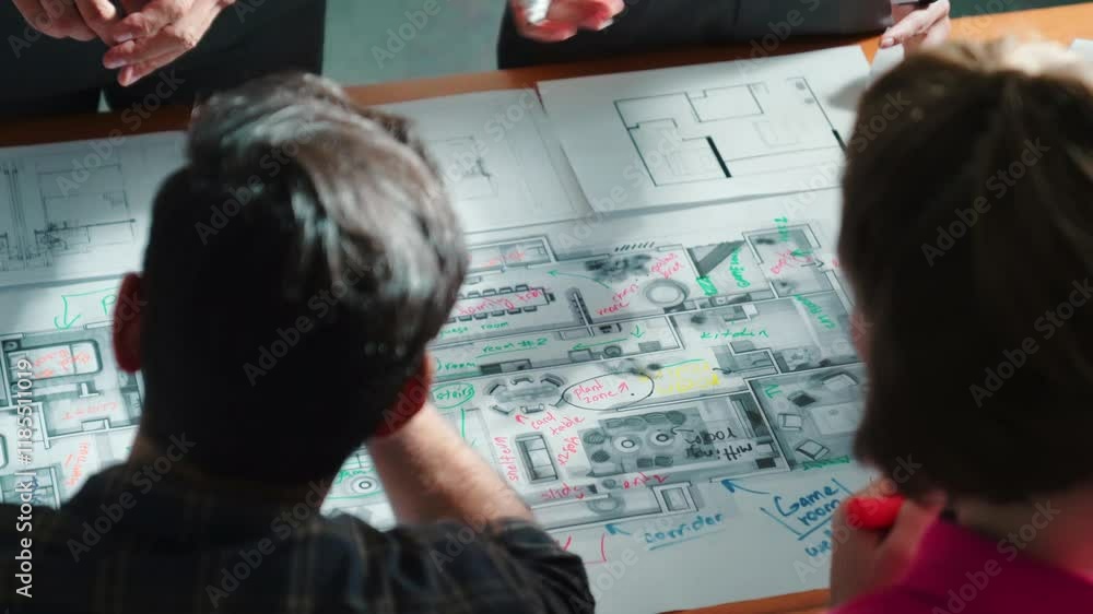 Poster top view of civil engineer team writing at blueprint at meeting table with color palettes. group of 
