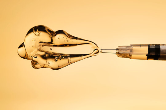 A drop of gel pours from a syringe for cosmetic procedures.