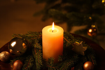Composition with burning candle, fir branches and Christmas decorations on table in evening, closeup