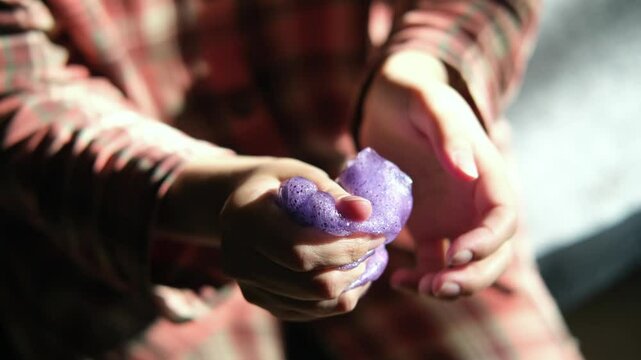 Playing with homemade purple slime, stretching the slime in the hands to the sides, an engaging sensory activity, concept for educational content, toy stores, and child development at home. 