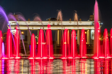 Long exposure image of colorful fountain sprays in gold and white neon illumination. Bright night in the Gorky Park in Moscow.