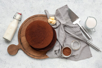 Composition with sponge cake layers, ingredients and utensils on light background