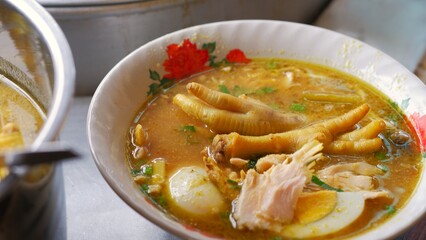 Chicken soup with shredded chicken, chicken feet, eggs, sliced cabbage, vermicelli in broth. Indonesia food.