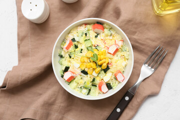 Bowl of salad with crab sticks, corn and cucumber on white background