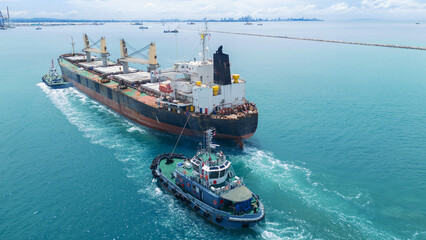 Naklejka premium Cargo Ship was pulling by Tugboat go to Maintenance port. cargo ship import export to customers sea port. export shipping industry freight and transportation logistics concept