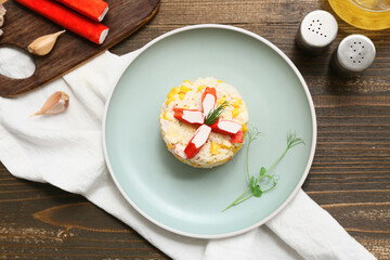 Bowl of salad with crab sticks and corn on wooden background