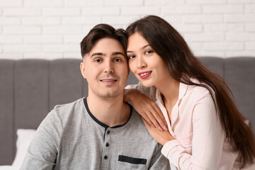 Fototapeta premium Young couple sitting together on bed