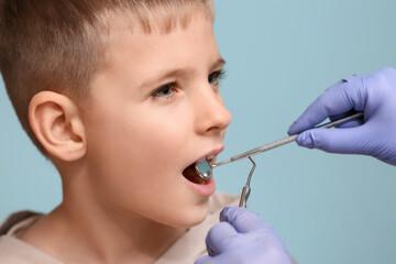 Obraz premium Dentist examining teeth of little boy on blue background