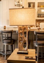 A modern decorative lamp with a textured base on a wooden table in a cozy kitchen with warm and neutral tones iPhone on the table