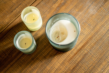 Three glass jar candles placed on a rustic wooden table