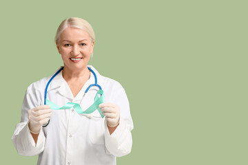 Mature female doctor with teal ribbon on green background. Cervical Health Awareness Month