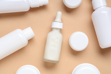 Jars and bottles with cosmetic products on beige background