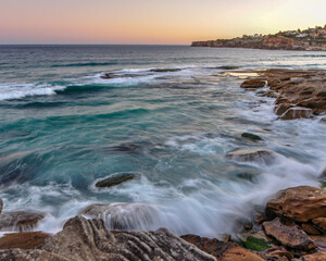 Waves crash into the rocks at Tamarama Point on the Sydney Coastline at sunset 