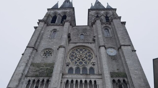 A Gothic church with twin spires, rose window, and clock in Blois, France