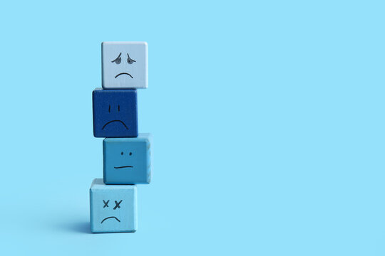 Cubes with drawn sad faces on blue background