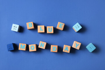 Wooden cubes with text BLUE MONDAY and drawn sad faces