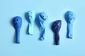 Balloons with drawn sad faces on blue background