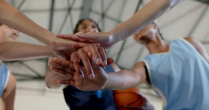 Basketball team huddling, stacking hands together before game, showing unity