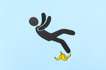 Falling paper human figure with banana peel on blue background. Loser concept