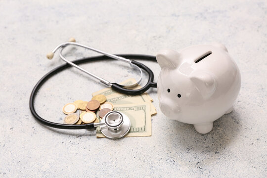 Piggy bank with stethoscope and money on grunge background
