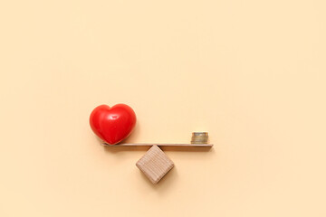 Coins with red heart on scales against beige background. Concept of balance