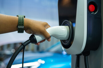 Hand is holding fast electric car charger green energy environment friendly driving vehicle station. Modern transport fuel of future. Minimal design power unit.