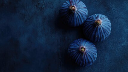 Beautiful fresh figs with vibrant blue violet skin on a textured dark blue background showcasing their natural elegance and detail.