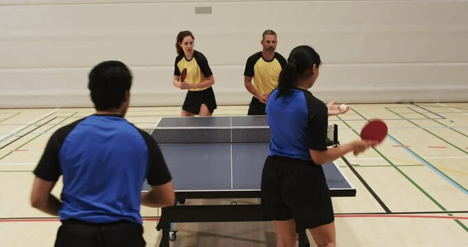 Playing table tennis, mixed doubles team in yellow uniforms competing indoors