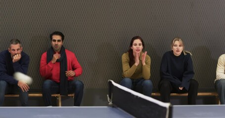 Watching table tennis match, group of people sitting on bench, smiling and engaged
