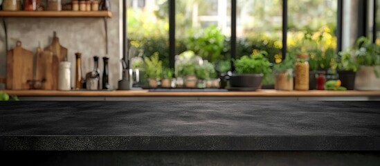 Black countertop in modern kitchen with blurred greenery background and empty space for text showcasing contemporary decor and culinary lifestyle.