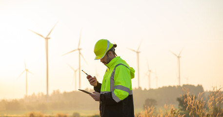 Engineer wearing uniform inspection and survey work in wind turbine farms rotation to generate...