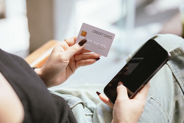 Close-up of young Asian woman using smartphone and credit card for mobile banking or online shopping. She represents modern e-commerce, digital transactions and financial technology.