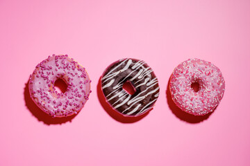 A colorful assortment of vibrant donuts with various toppings arranged on a pink