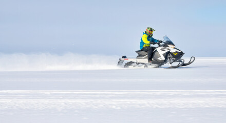Male riding snowmobile on vast snowy landscape in winter adventure scene
