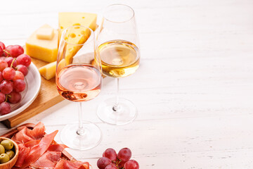 A delectable arrangement of various cheeses, fresh grapes, prosciutto and wine