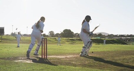 Playing cricket on sunny day, female players batting and fielding on grass field - Powered by Adobe