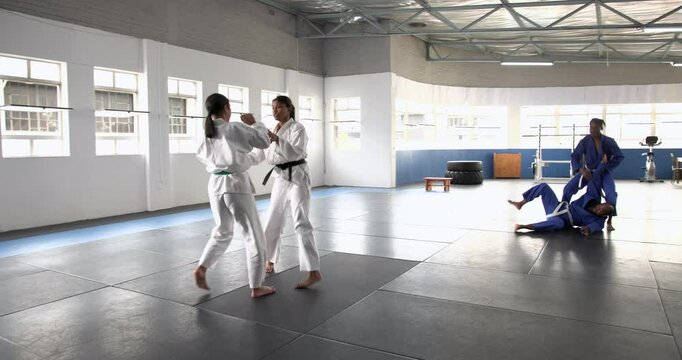 Practicing judo, two athletes sparring in dojo, wearing traditional uniforms