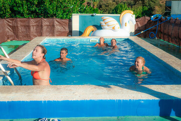 Five mature friends are having fun and relaxing in a swimming pool during a sunny day, enjoying the cool water and each other's company, with an inflatable pegasus toy floating nearby