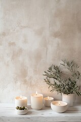 candles and olive branches against a beige wall