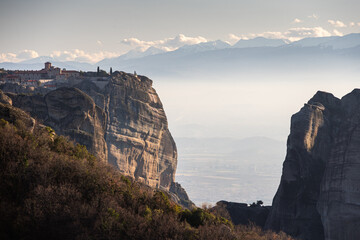 Travel to Meteora. The Monastery of Holy Trinity photographed in amazing sunset light with mountains in foreground. Travel to Orthodox iconic place of Meteora in Greece.