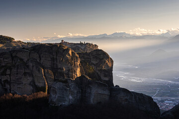 Travel to Meteora. The Monastery of Holy Trinity photographed in amazing sunset light with mountains in foreground. Travel to Orthodox iconic place of Meteora in Greece.