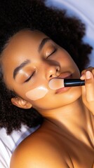 Obraz premium Close-Up young Afro-Latina woman Applying Liquid Foundation with Makeup Brush