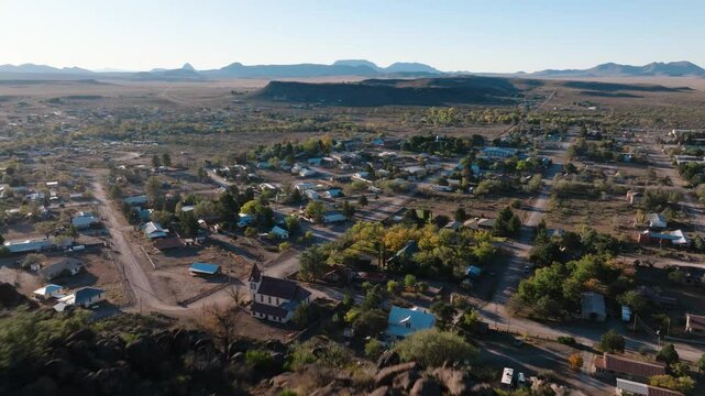 Flying over mountain to reveal small rural West Texas Town, Fort Davis near Big Bend National Park, drone push in at golden hour in 4k