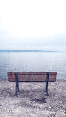 Wooden bench by the sea. Bench in rainy, moody weather. Metaphorical meaning of loneliness,...