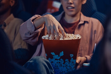 Close up of woman eating popcorn during movie screening in theatre.