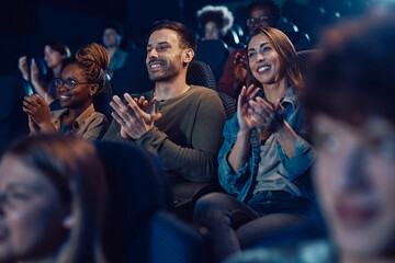 Happy audience applauding after movie premiere at cinema.